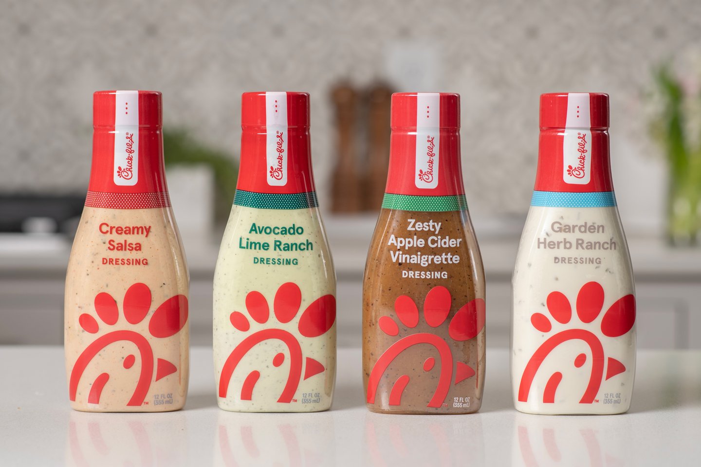 Bottles of Avocado Lime Ranch, Creamy Salsa, Garden Herb Ranch and Zesty Apple Cider Vinaigrette in a line.