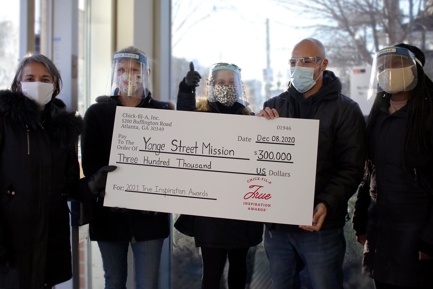 a group of people holding a large True Inspiration award check