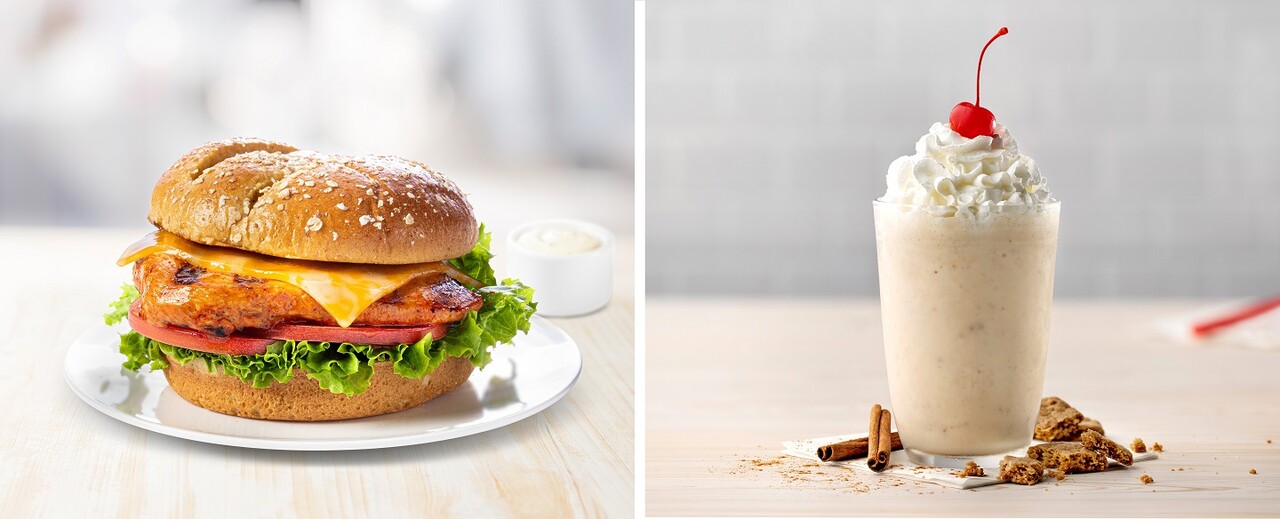 An image of the Grilled spicy Deluxe Sandwich topped with cheese and on lettuce and tomato sitting on a white place next to an image of the Autumn Spice Milkshake in a glass topped with whipped cream and a cherry