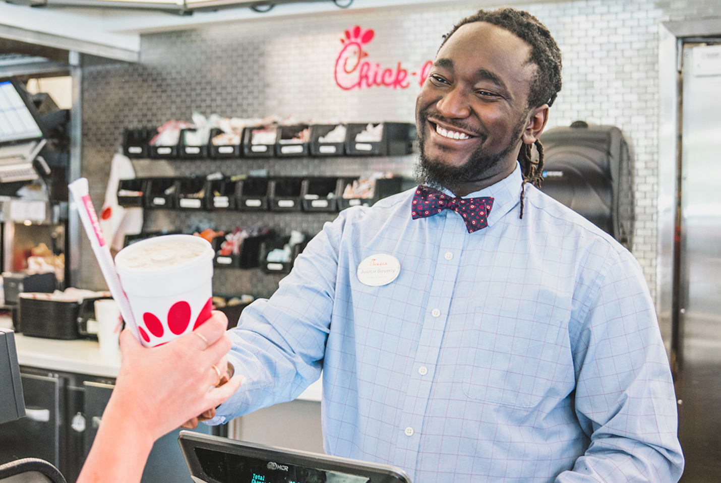 A Chick-fil-A Team Member in a restaurant hands a customer their drink. 