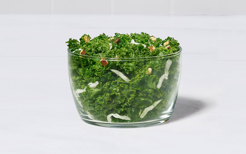 A glass bowl of our Kale Crunch Side on a white counter
