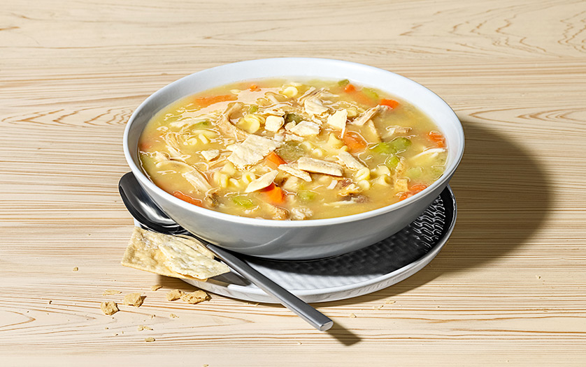 A bowl of Chicken Noodle Soup on a wooden counter