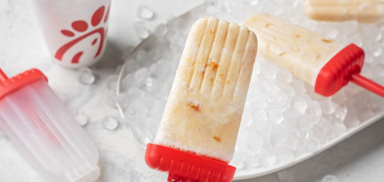 Peach Milkshake Ice Pops on a platter of ice with a Peach Milkshake cup next to them 