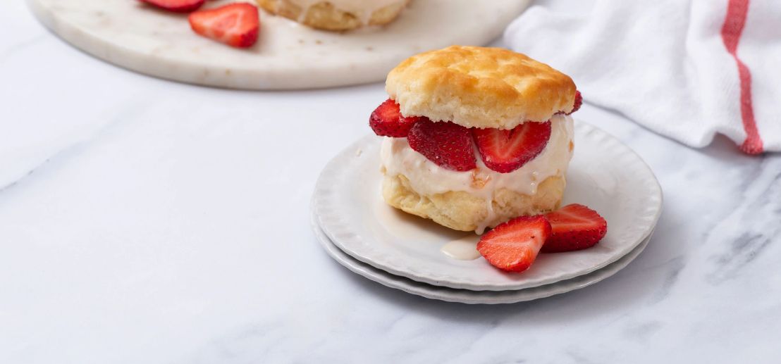 Strawberry Peach Shortcake Ice Cream Sandwich on a white plate with slices of strawberries next to it