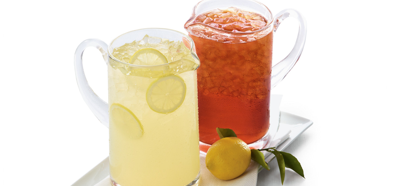 A pitcher of Chick-fil-A lemonade with sliced lemons next to a pitcher of Chick-fil-A Sweetened Iced Tea.