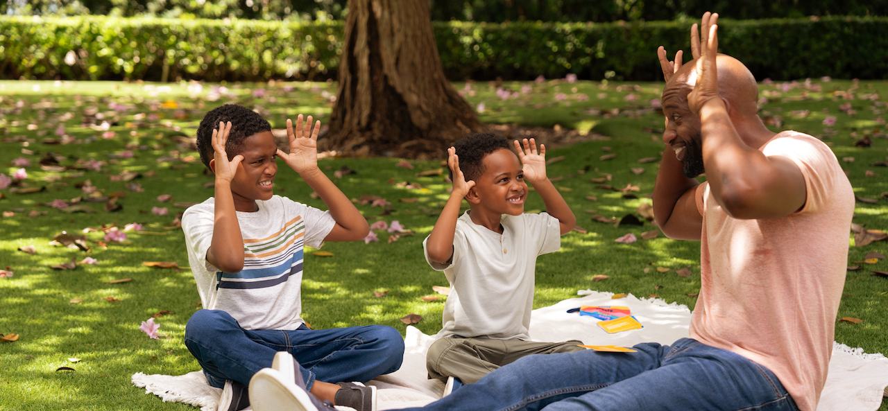 Father and sons sitting outside playing Mix It Up® Activity Box from pennycake® 