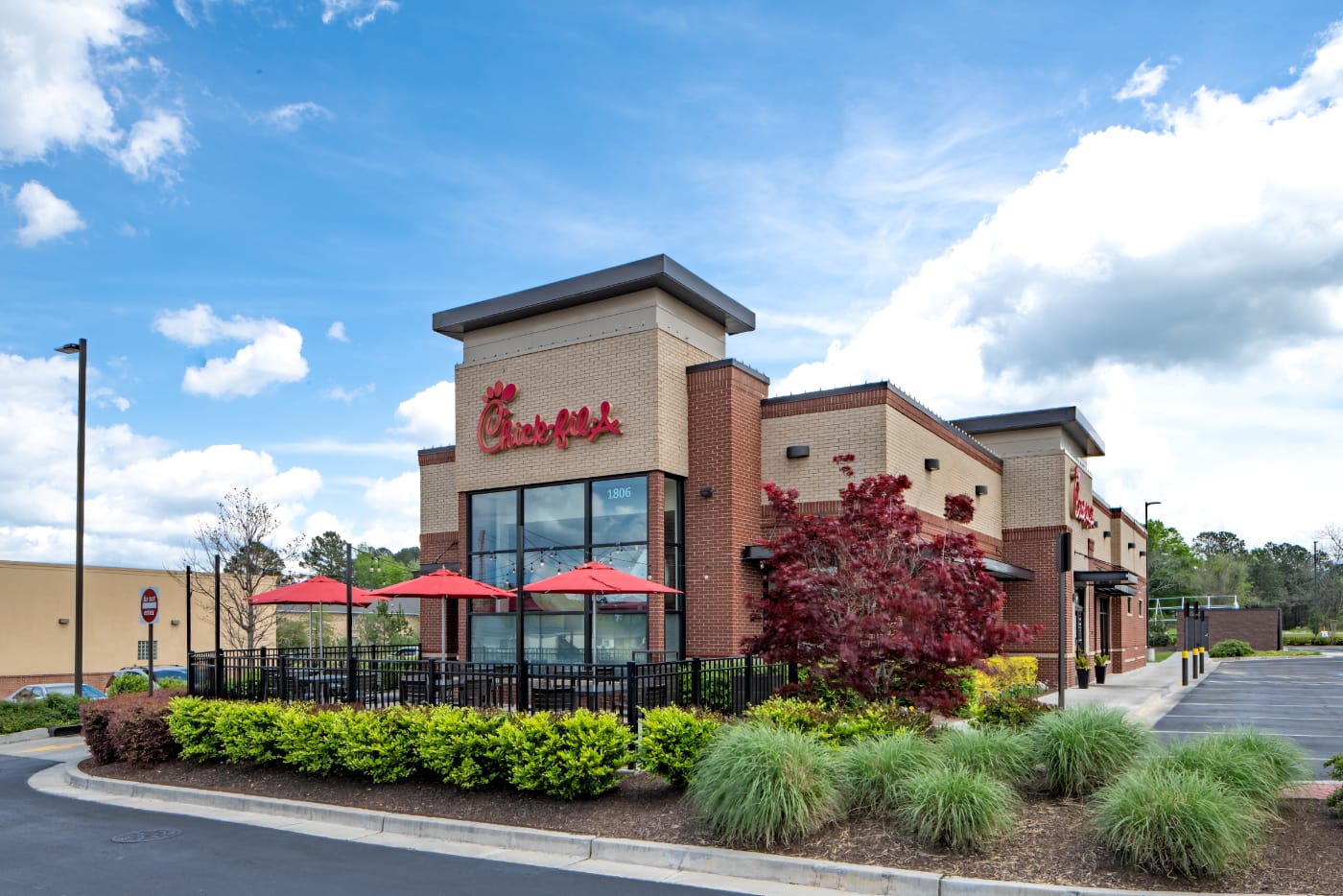 Exterior of Chick-fil-A restaurant with three tables with red umbrellas.