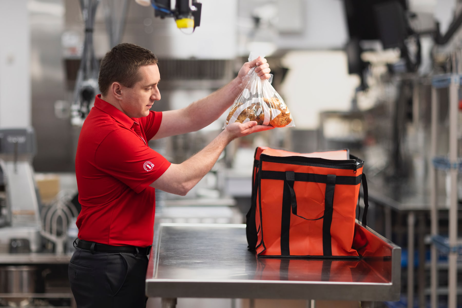 Chick-fil-A team member puts food into a red catering bag.