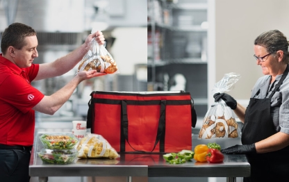 Chick-fil-A team members putting food into a large red catering bag.