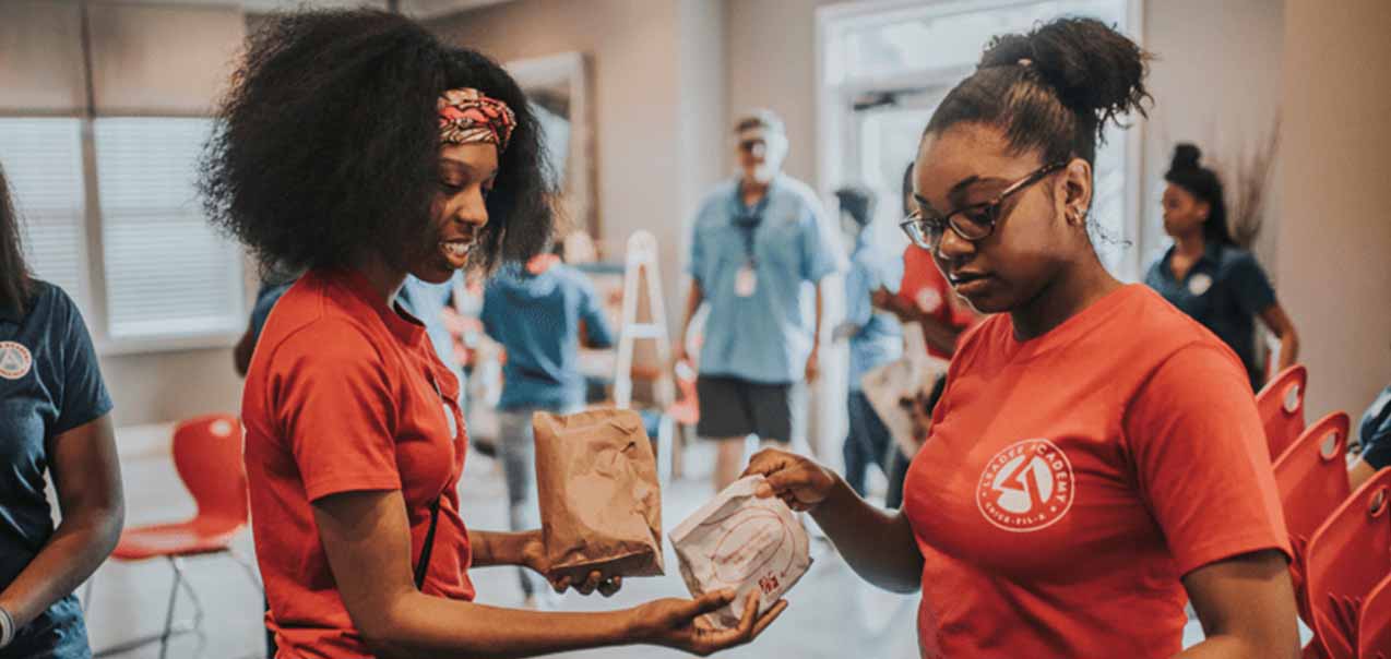 Chick-fil-A Leader Academy participants distributing Chick-fil-A food at an event.