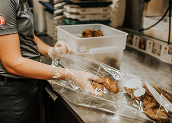 A Chick-fil-A Team Member packaging chicken filets through the Shared Table program. 