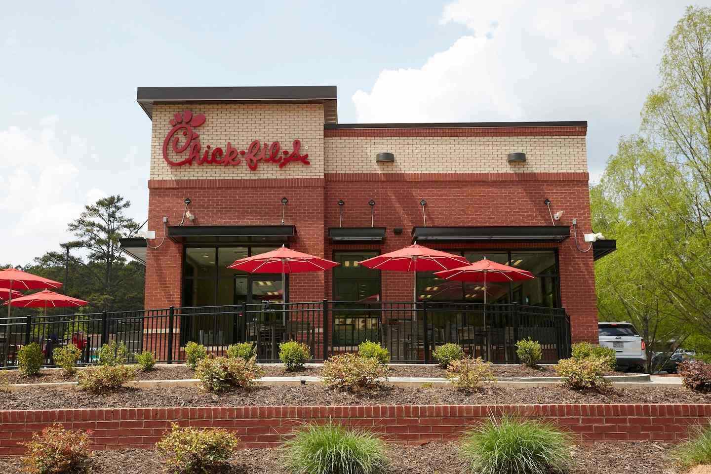 The exterior of a brick Chick-fil-A restaurant with red Chick-fil-A signage. 