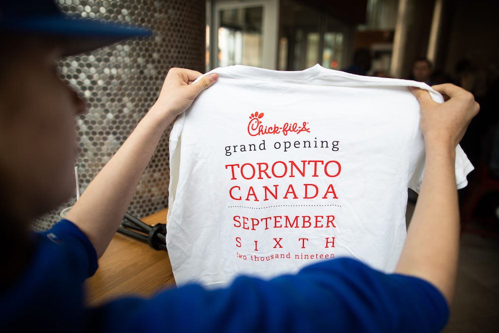 Photo of a Chick-fil-A Team Member holding a commemorative t-shirt from the Chick-fil-A Yonge & Bloor opening day.