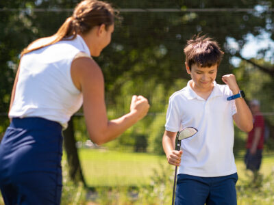 A woman and young boy in white shirts playing in a field.