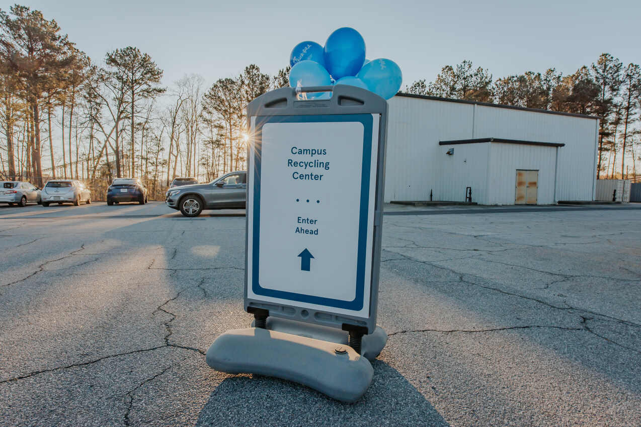 Recycling center sign with blue balloons tied on top.