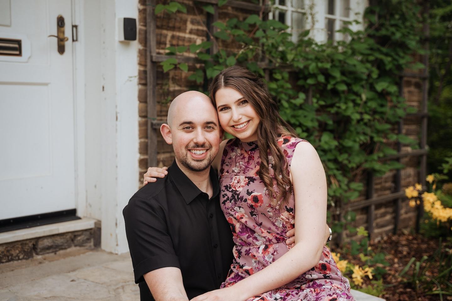 Julia Calandra, the new Owner-Operator of Chick-fil-A Newmarket East, sitting on her husband's lap on a front porch. 