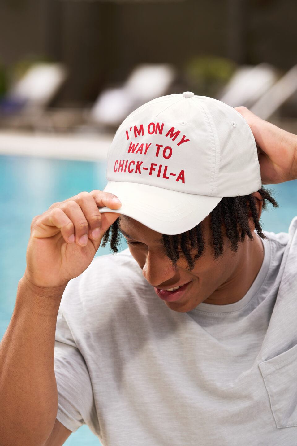 A male model wearing the new Chick-fil-A Hat from the 2024 Summer Merchandise Launch that reads "I'M ON MY WAY TO CHICK-FIL-A".