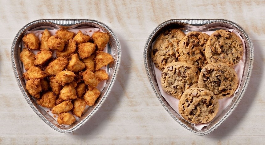 Two Chick-fil-A Heart Shaped Trays filled with Nuggets and Chocolate Chunk Cookies sitting on a table.