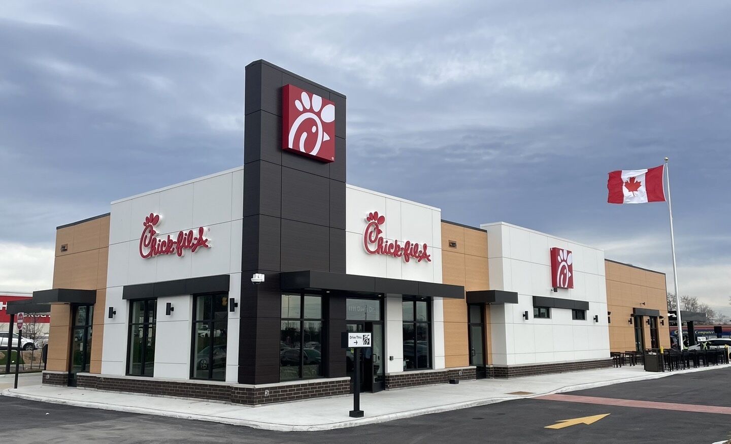 A Chick-fil-A restaurant exterior with a Canadian flag on a flagpole waving.