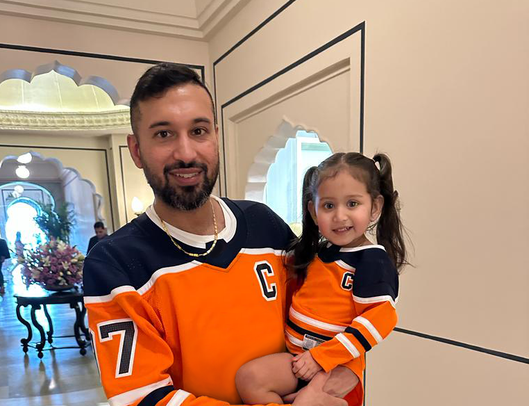 Jag Dhanju, Canada Owner-Operator, and his daughter smile in matching orange hockey-style jerseys.