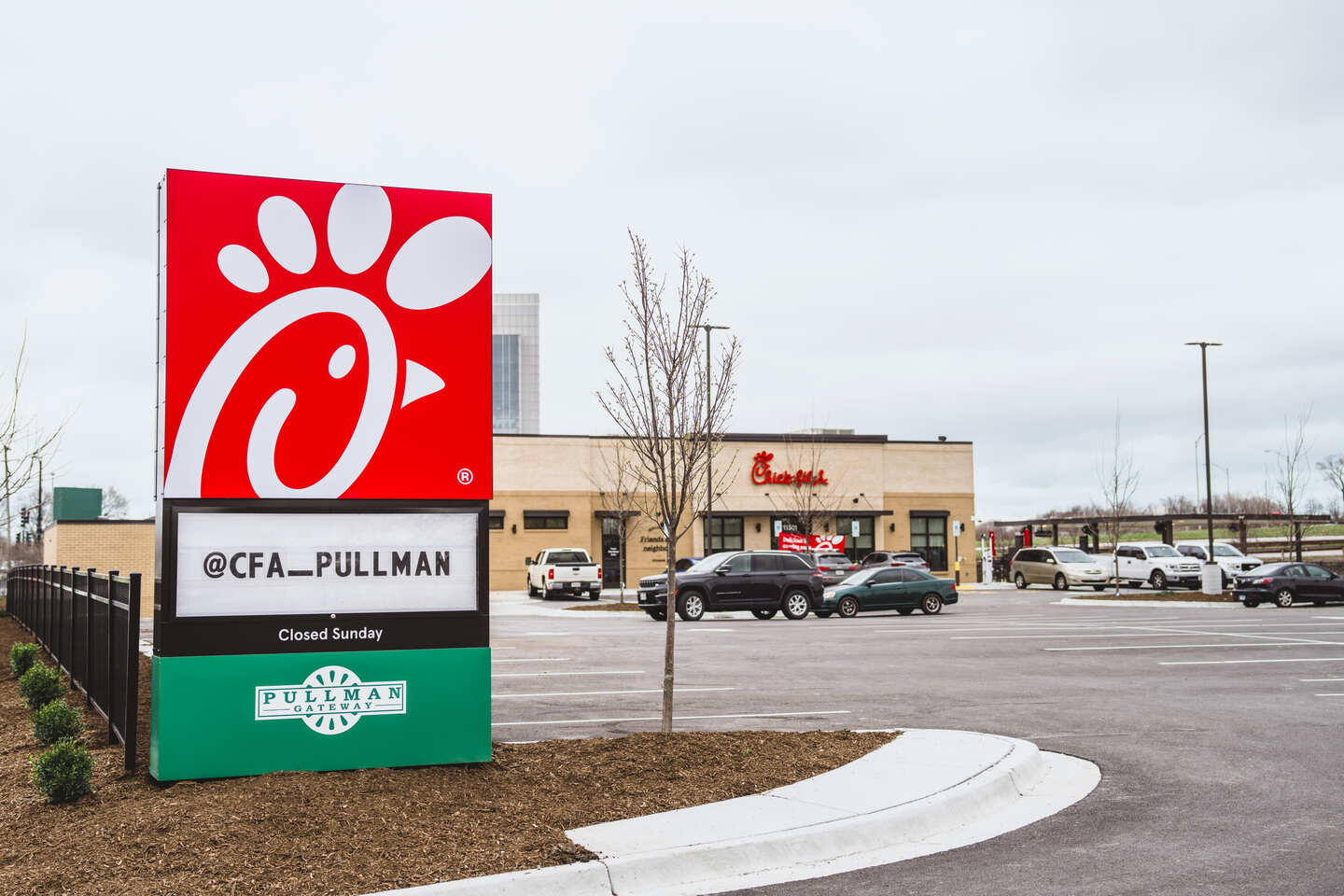 Chick-fil-A Pullman exterior with branded sign, parking lot, and restaurant building in the background.