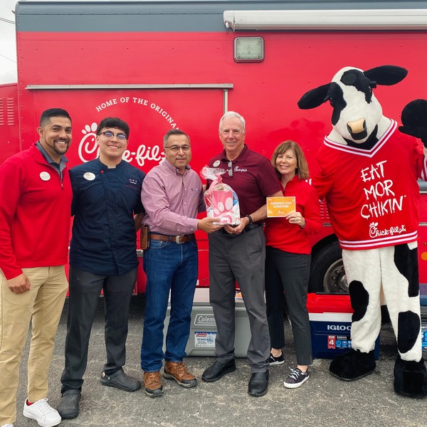 The San Antonio Chick-fil-A team and The Cow posing in front of their mobile food truck.