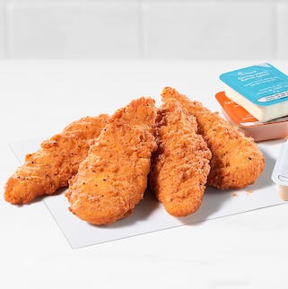 4-count Spicy Chick-fil-A Chick-n-Strips® next to packets of Garden Herb Ranch Sauce, Zesty Buffalo Sauce and Chick-fil-A® Sauce on a white countertop with a white tiled background