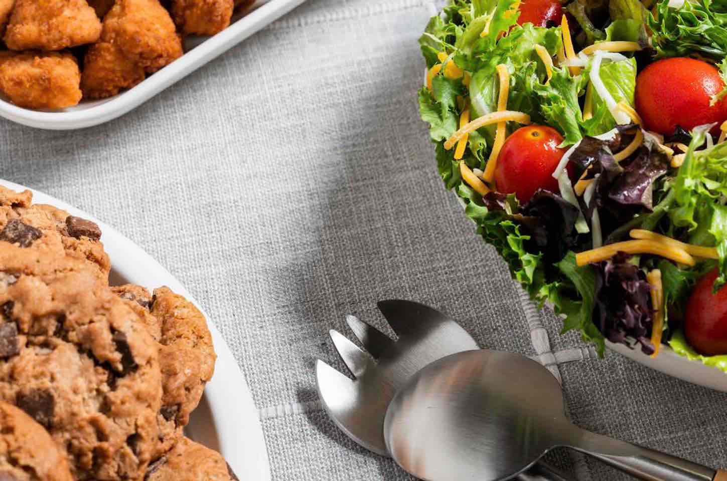 A Chick-fil-A catering order which includes trays of Side Salad, Chocolate Chunk Cookies and Chick-fil-A Nuggets.