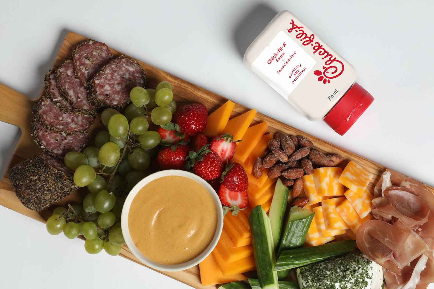 A shot of a bottle of 8 oz Chick-fil-A Sauce® paired with a charcuterie board.