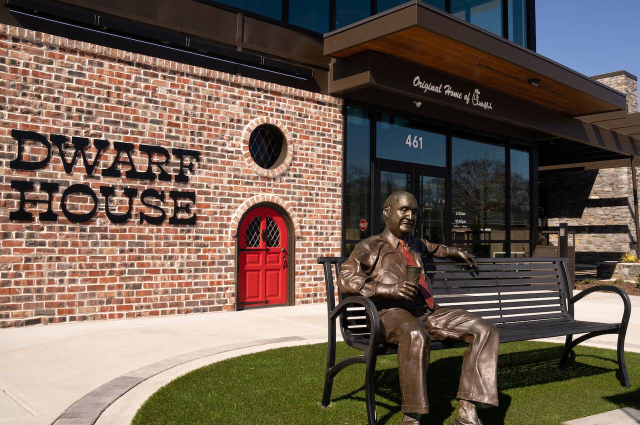 Bronze statue of S. Truett Cathy sitting on a bench outside of The Dwarf House