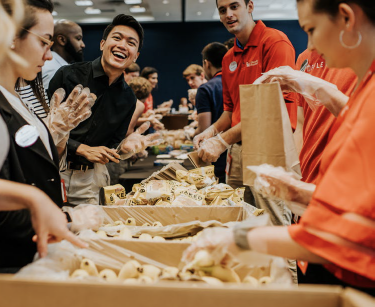 Group of Chick-fil-A® employees packing meals in bags