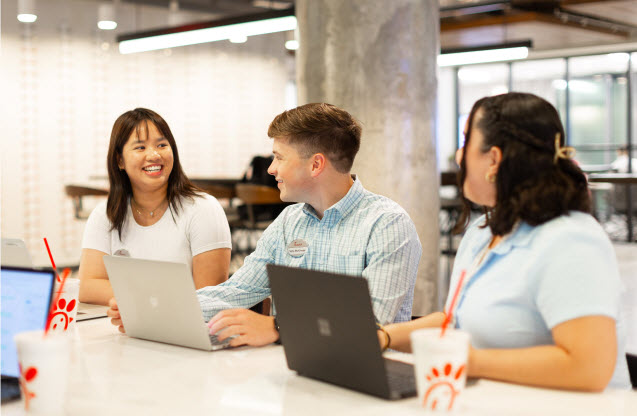 Three people sitting together with their laptops