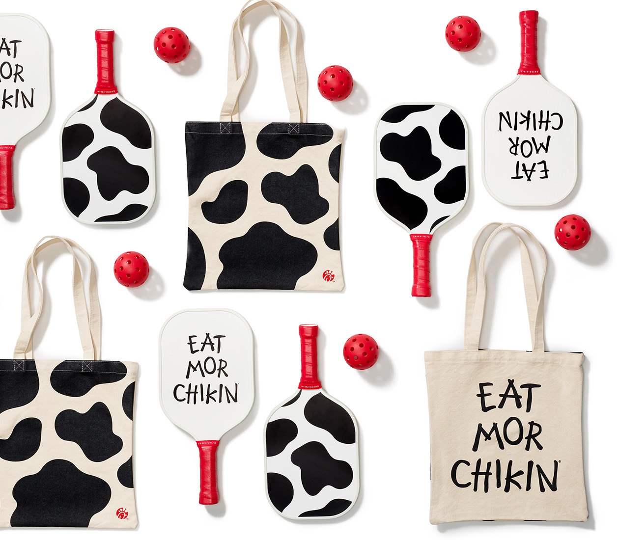 Red pickleballs, cow print and “Eat Mor Chikin” pickleball paddles, and cow print and “Eat Mor Chikin” canvas bags   New merch header: New