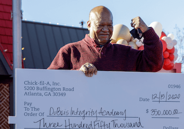 Smiling man holding check from True Inspiration Awards