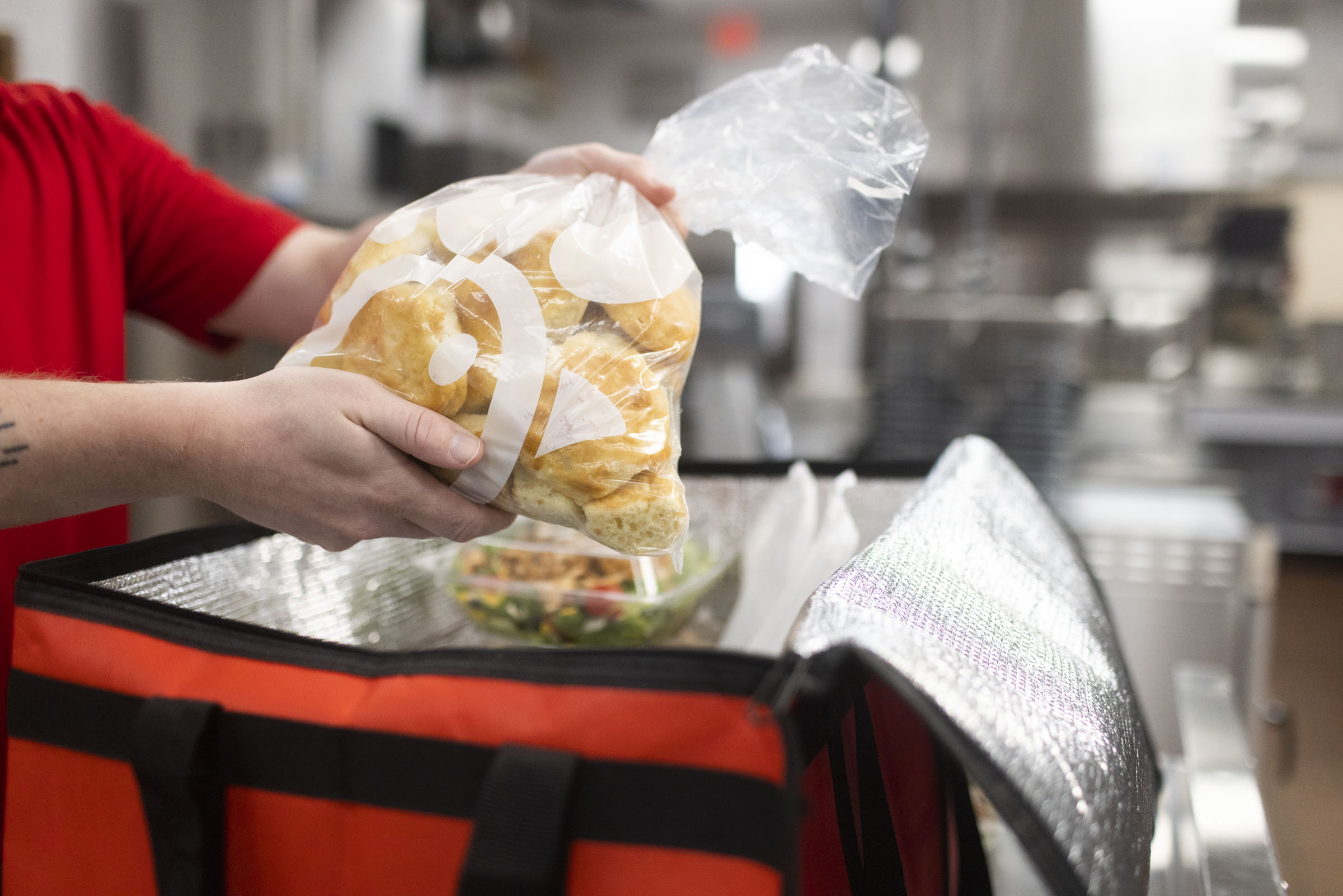 A person placing a bag of Buttery Biscuits into an insulated bag