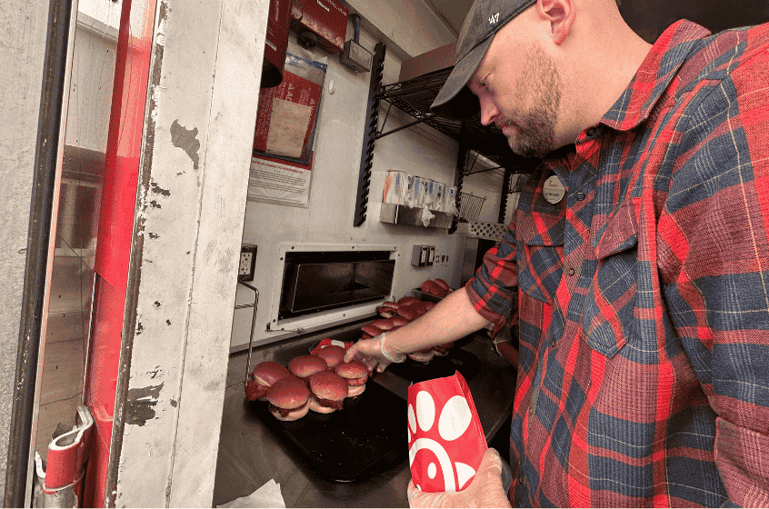 A Team Member taking a Chick-fil-A® Chicken Sandwich off a warming station inside and placing it in a package.