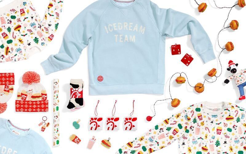 Items from Chick-fil-A® Originals Holiday Collection spread out including Icedream Team Crewneck, Very Merry Pom Beanies, Very Merry Crewnecks and more.