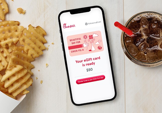 Overhead photograph of smartphone sitting next to Waffle Potato Fries and a soft drink and with its screen showing a Chick-fil-A eGift card ready to purchase