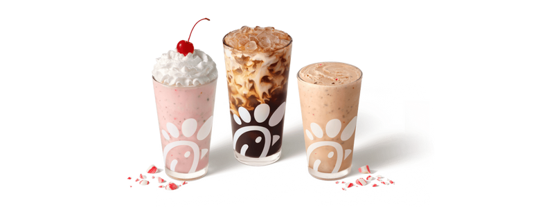 Overhead view of glasses of Peppermint Chip Milkshake, Peppermint Iced Coffee, and Peppermint Chip Frosted Coffee sitting together, next to pieces of peppermint