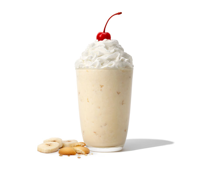 Banana Pudding Milkshake in a glass on a white background with bananas and wafers 