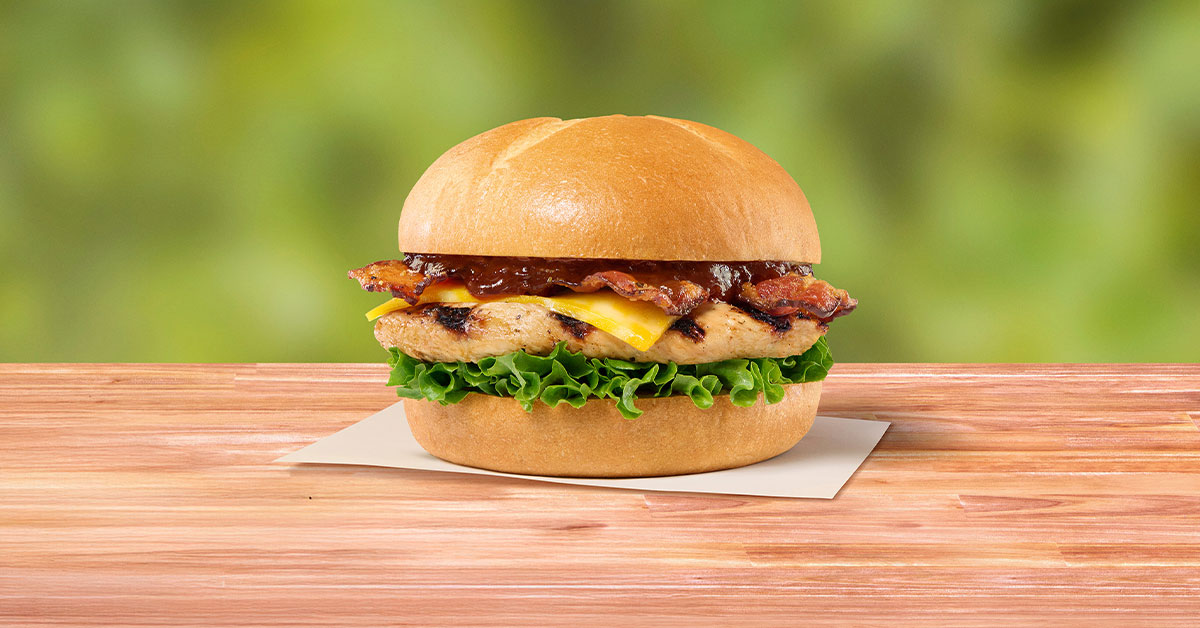 Smokehouse BBQ Bacon Sandwich with Grilled filet sitting on a napkin on a wooden table