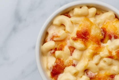 A white ramekin of Mac & Cheese on a marble table 
