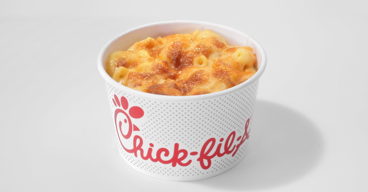 A person holding the Chick-fil-A® Chicken Sandwich on a counter with Waffle Potatoe Fries