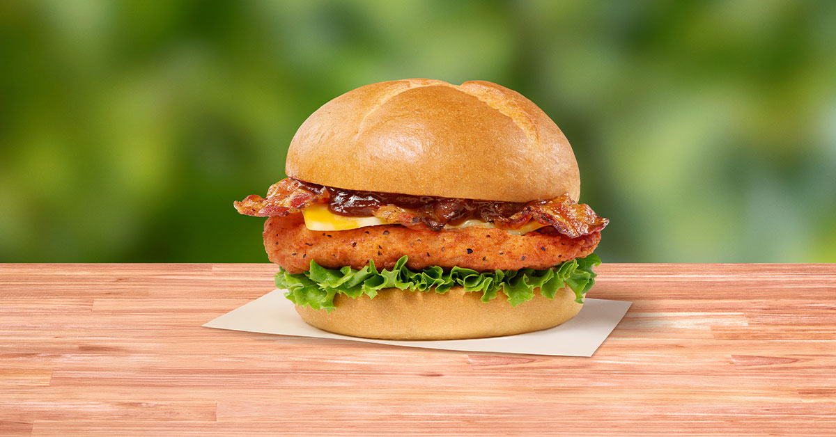 Smokehouse BBQ Bacon Sandwich with Spicy filet sitting on a napkin on a wooden table