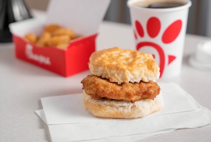 Chick-fil-A® Chicken Biscuit on white napkins sitting in front a box of Hashbrown and a cup 
