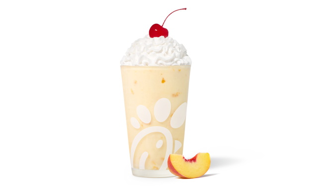 A glass of a Peach Milkshake with a peach slice next to it
