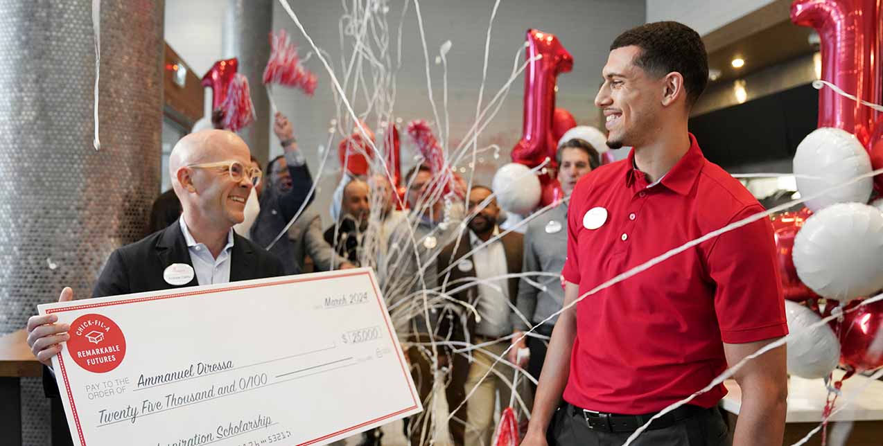 Chick-fil-A  CEO Andrew Cathy hands a large check to Ammanuel D, a Chick-fil-A Team Member and 2024 True Inspiration Scholarship recipient