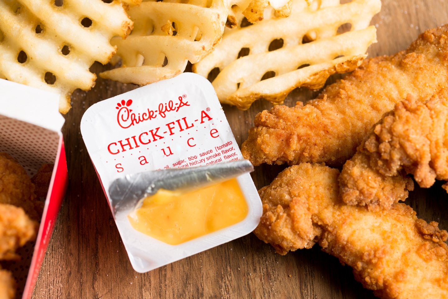 Chick-fil-A Sauce surrounded by Chick-n-Strips and Waffle Fries 