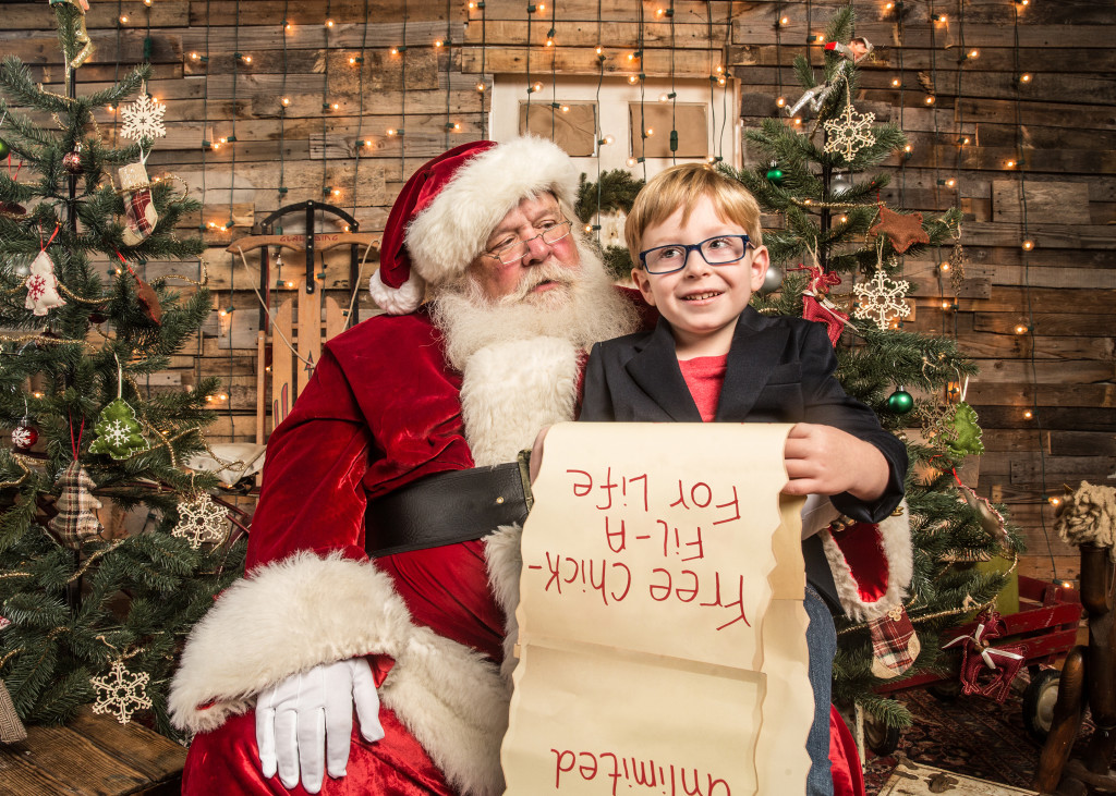 Little boy sitting on santa's lap with his christmas list reading "free Chick-fil-A for life"