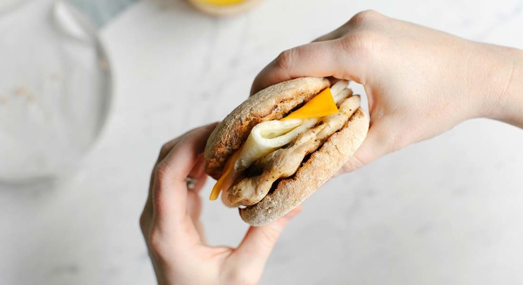 Egg white grill with egg whites, American cheese, and grilled chicken on a toasted English Muffin
